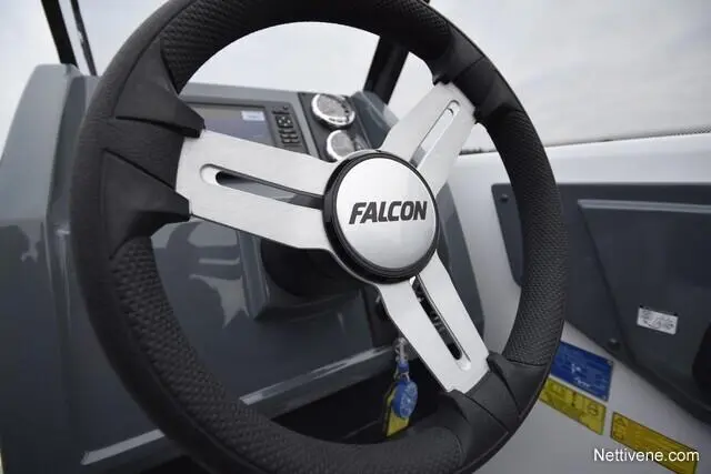 Close-up of a Falcon boat steering wheel with a digital display and controls in the background, showing marine features.